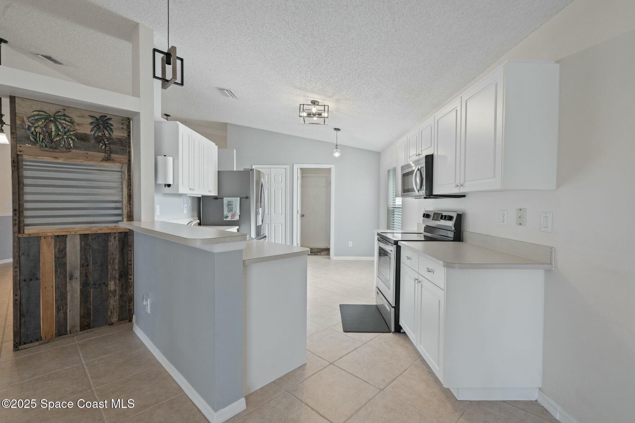 2405 Bayhill Drive Melbourne, FL 32940 - Photo 6 of 36 a kitchen with white cabinets and stainless steel appliances