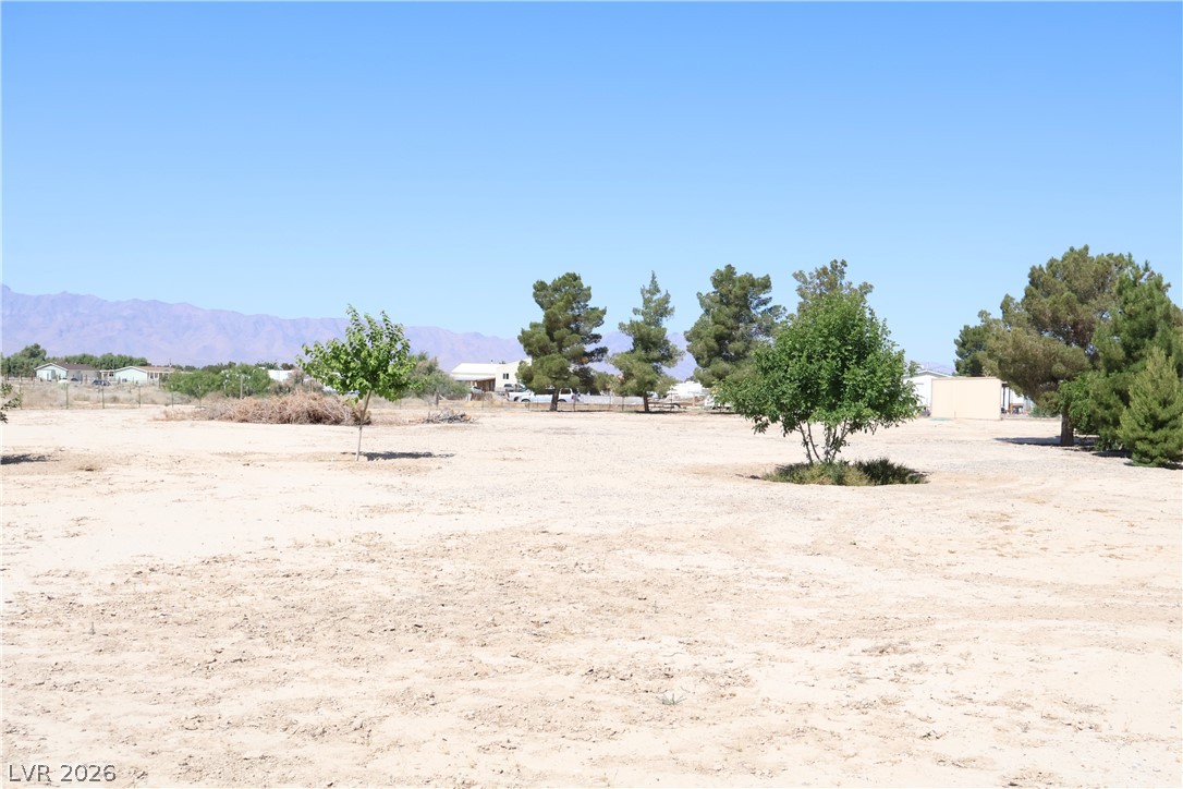 4501 East Kellogg Road Pahrump, NV 89061 - Photo 38 of 52 A spacious desert lot awaits your vision, framed by distant mountains and a clear sky.