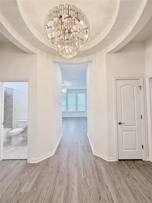 1336 Morning View Road Georgetown, TX 78628 - Photo 4 of 40 A grand chandelier illuminates the arched hallway, leading to a sun-filled room with wood flooring.