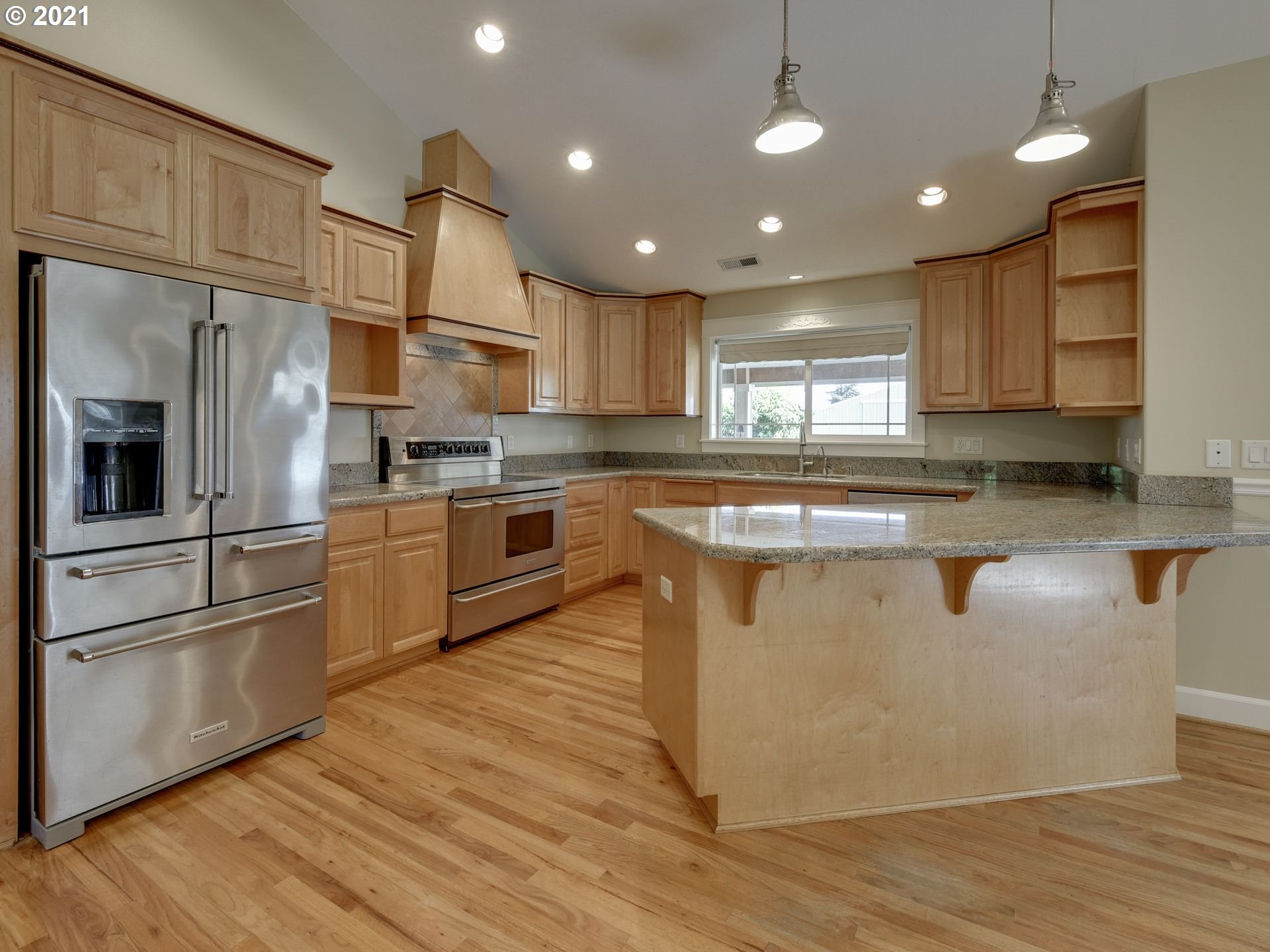 5171 South Elliott Prairie Road Woodburn, OR 97071 - Photo 7 of 32 a kitchen with stainless steel appliances granite countertop a sink a stove a refrigerator and island with wooden floor