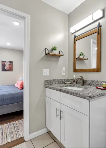 a en suite bathroom with a granite countertop sink and a mirror