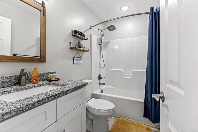 a bathroom with a granite countertop sink toilet and shower