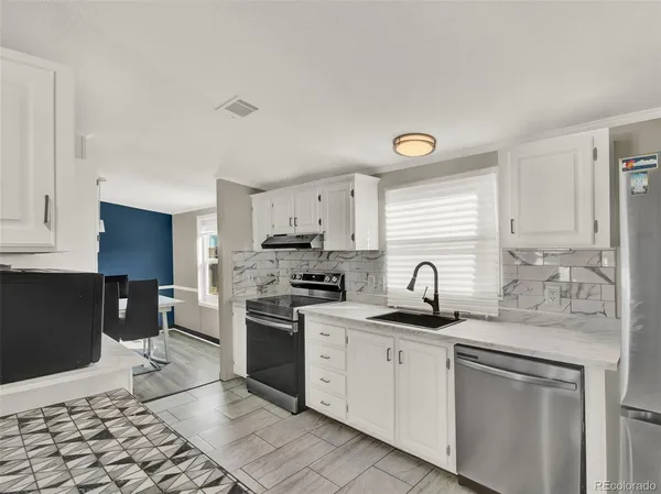 a kitchen with granite countertop a sink cabinets stainless steel appliances and a window