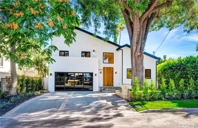 a front view of a house with a garden and trees
