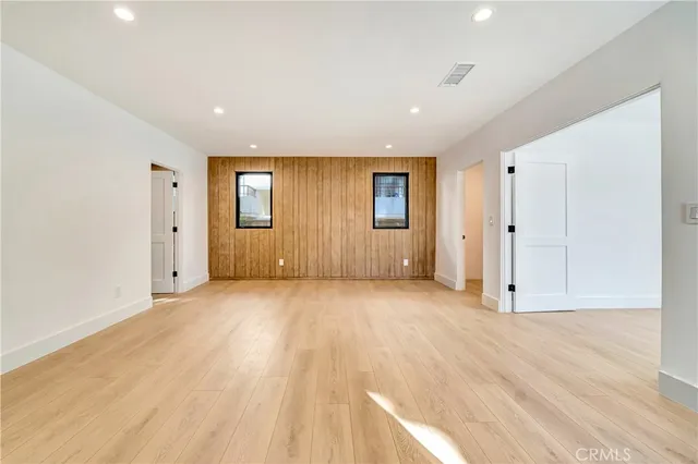 a view of an empty room with wooden floor and windows
