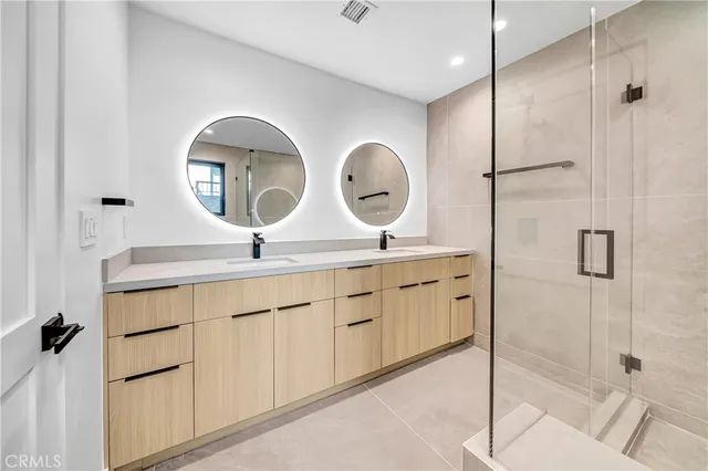 a bathroom with a double vanity sink mirror and shower