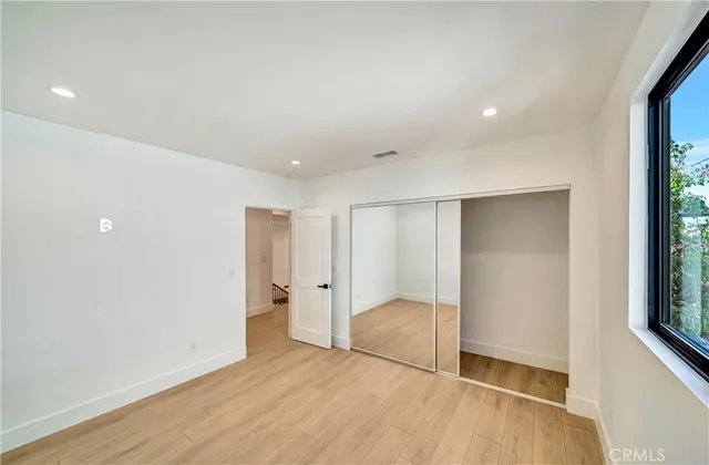 a view of a hallway with wooden floor and a bathroom