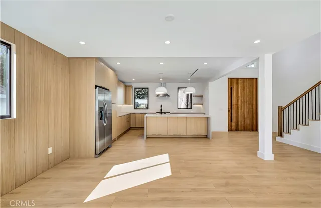 a large kitchen with kitchen island a stove a sink a center island and wooden floor