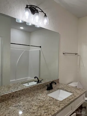 a bathroom with a granite countertop sink and a mirror