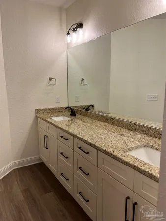 a bathroom with a granite countertop sink and white cabinets