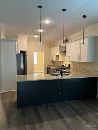 a kitchen with stainless steel appliances granite countertop a sink a stove a refrigerator and wooden floor