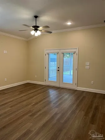 a view of an empty room with wooden floor and a ceiling fan