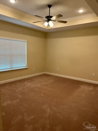 an empty room with a chandelier fan and windows