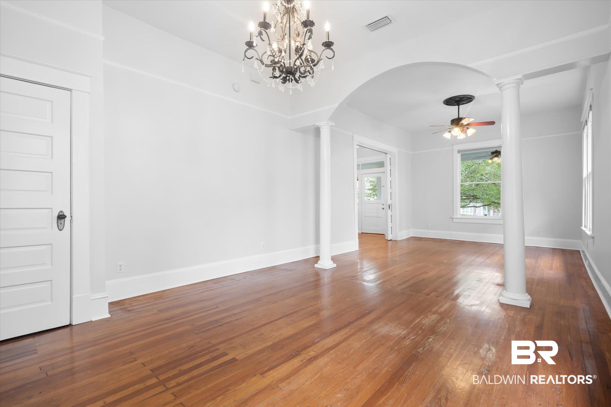 14 South Monterey Street Mobile, AL 36604 - Photo 38 of 41 Unfurnished living room with hardwood / wood-style flooring, ceiling fan with notable chandelier, and ornate columns