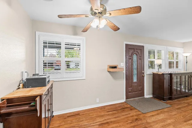 a view of an empty room with window hardwood floor and a ceiling fan