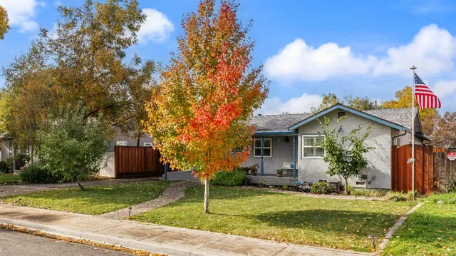 a front view of a house with a garden and trees
