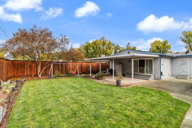 a view of backyard with wooden fence and a large tree