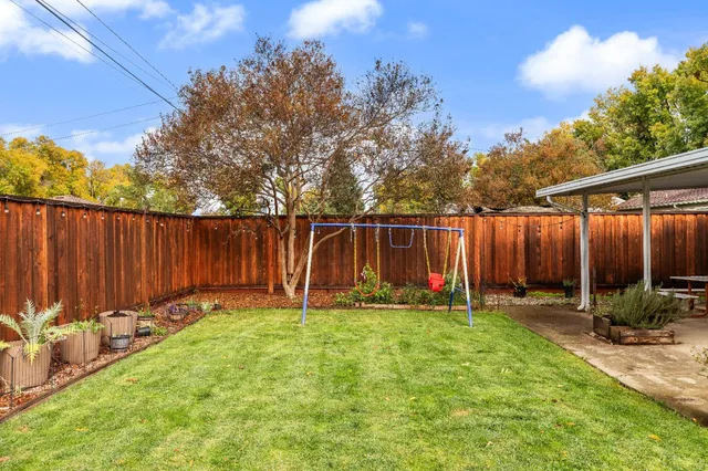 a view of a backyard with a slide trees and wooden fence