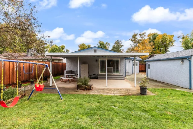 a view of a house with a yard and a large tree