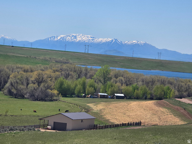 8400 North Treasurton Road, Unit CITY Preston, ID 83263 - Photo 6 of 12 Spacious rural landscape featuring a detached outbuilding with a gray metal roof, partially fenced pastures, and distant snow-capped mountains