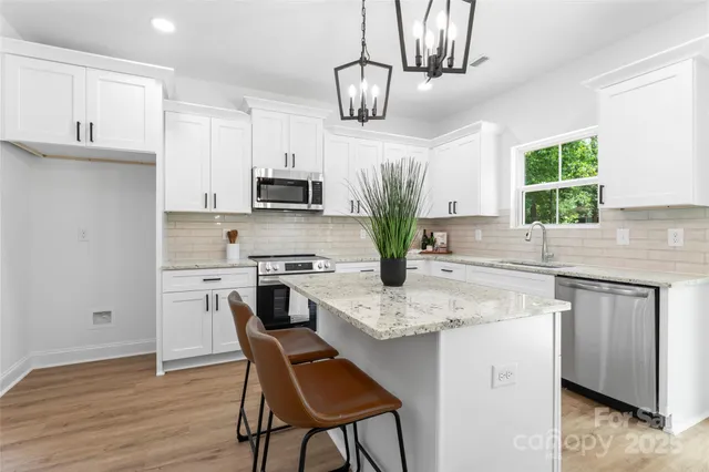 a kitchen with stainless steel appliances granite countertop a kitchen island a stove a sink dishwasher a microwave oven with a dining table and chairs