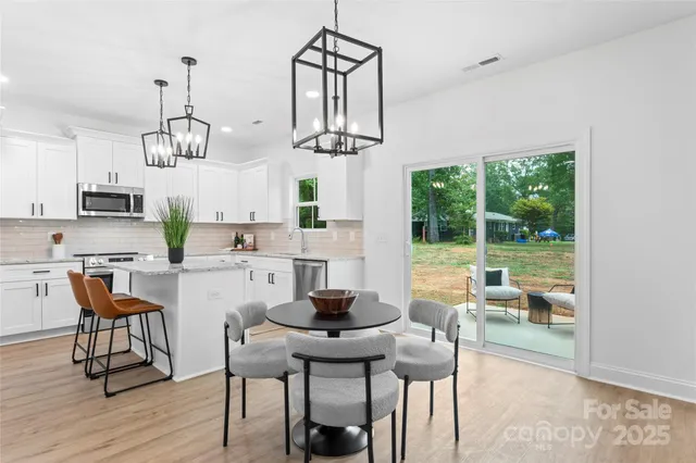 a dining room with wooden floor a chandelier a glass table and chairs