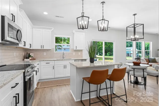 a kitchen with stainless steel appliances kitchen island a large window and white cabinets