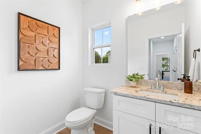 a bathroom with a granite countertop toilet a sink and mirror