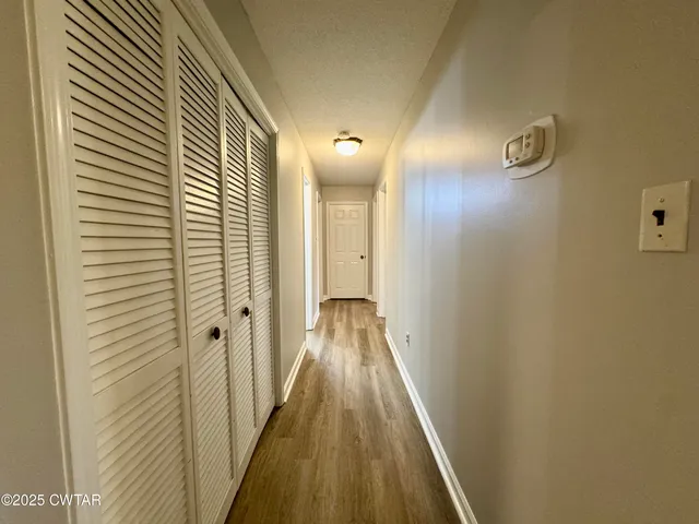 an empty room with windows and chandelier fan