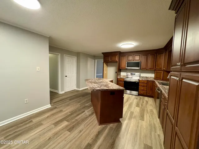 a kitchen with stainless steel appliances granite countertop a stove and a wooden floors