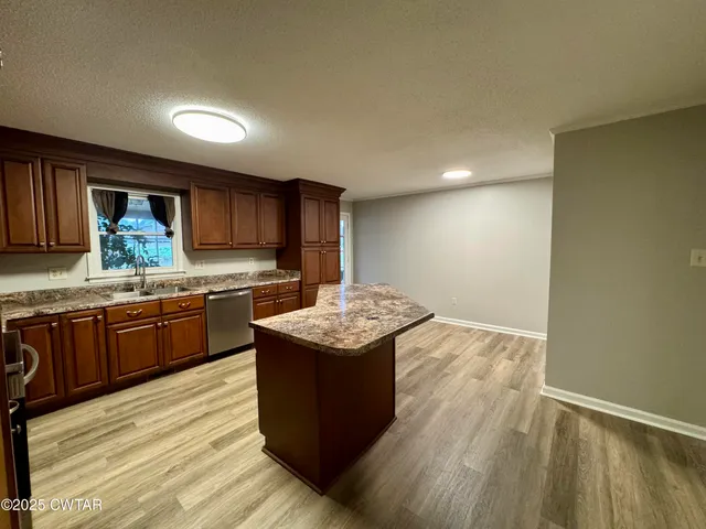 a kitchen with stainless steel appliances granite countertop a stove top oven a sink dishwasher a refrigerator and a cabinets with wooden floor