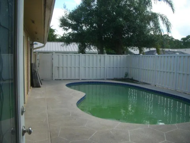 a view of a house with a big yard and palm trees