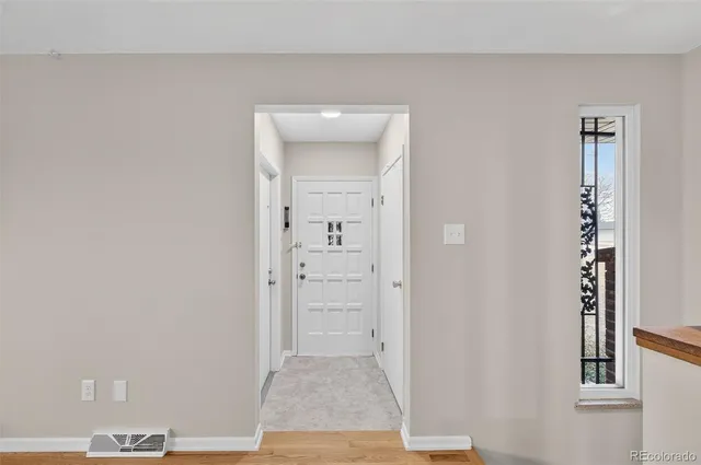 an empty room with wooden floor cabinet and windows