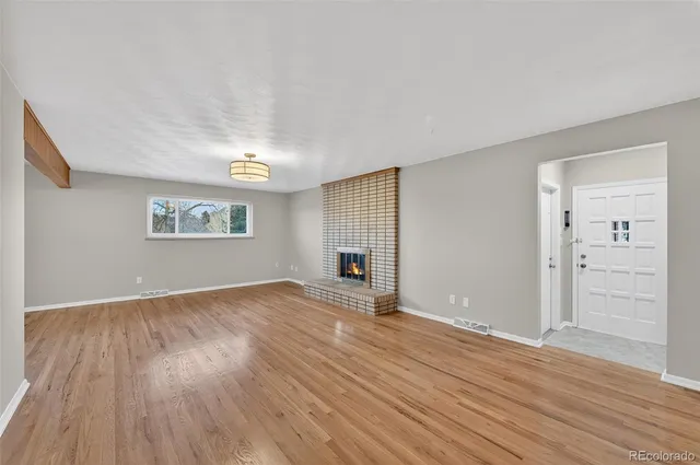 a view of empty room with wooden floor and fireplace