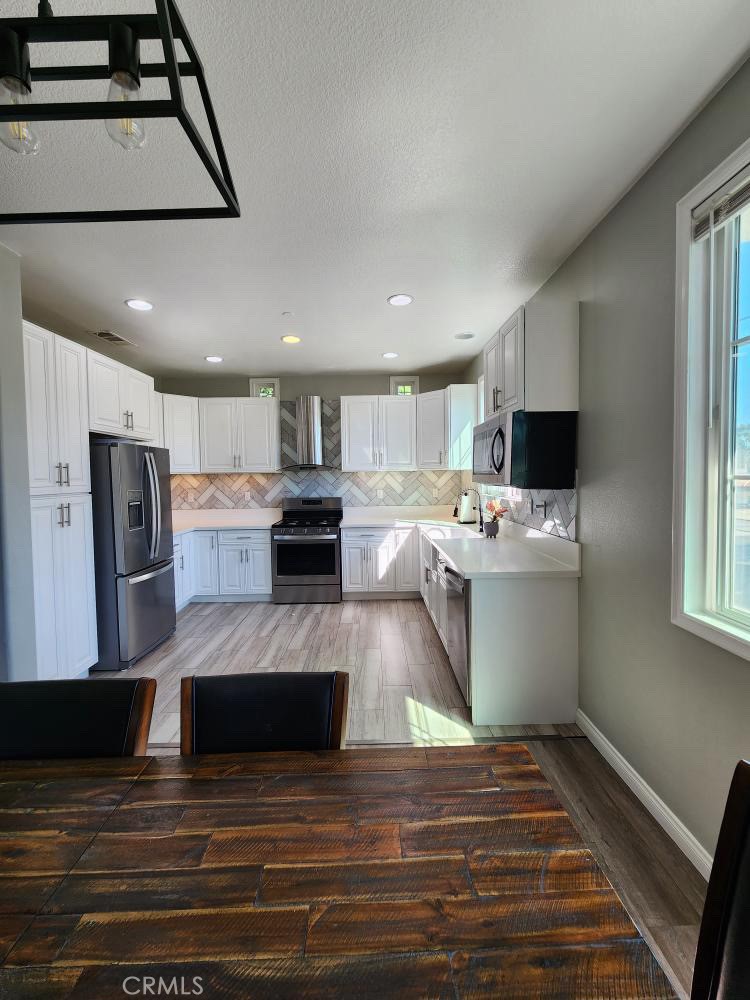 11040 Encanto Way El Monte, CA 91731 - Photo 3 of 17 a large kitchen with stainless steel appliances kitchen island granite countertop a refrigerator stove oven a sink dishwasher and white cabinets with wooden floor