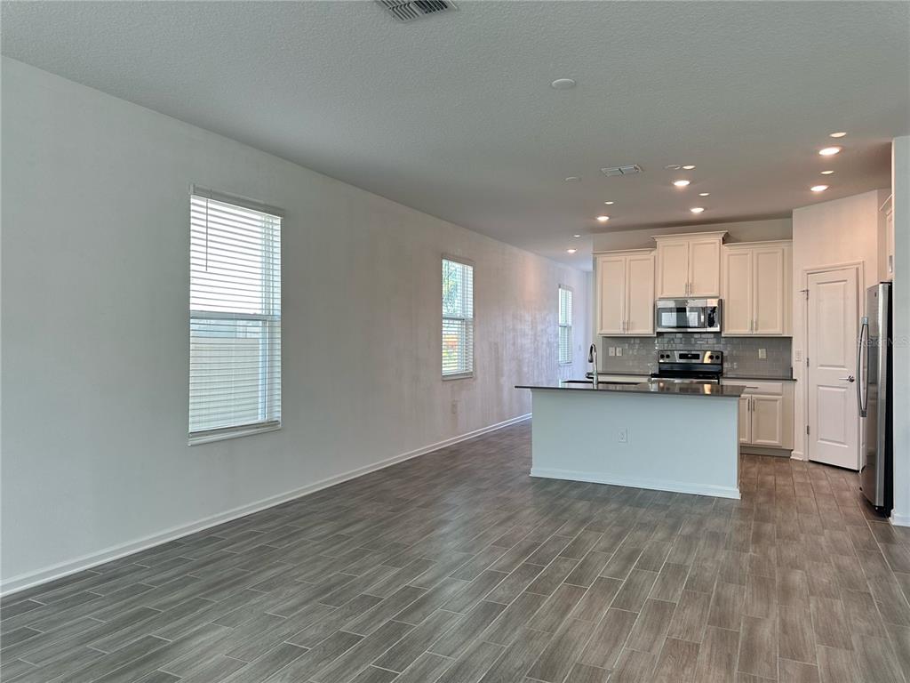17136 Salty Dog Road Winter Garden, FL 34787 - Photo 5 of 38 a kitchen with stainless steel appliances granite countertop a stove a refrigerator a sink a microwave oven with white cabinets and wooden floor