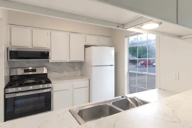 a kitchen with granite countertop a sink cabinets and stainless steel appliances