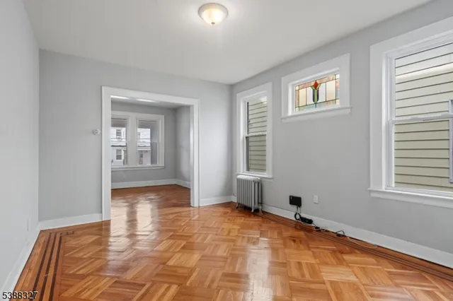 a view of an empty room with window and wooden floor