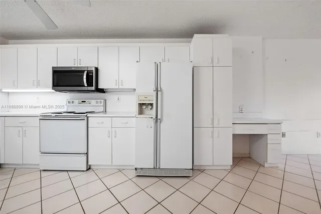 a kitchen with white cabinets and appliances
