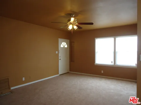an empty room with windows and fan