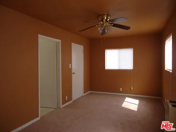 an empty room with windows and fan