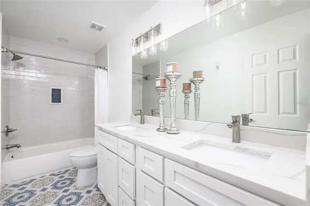 a bathroom with a double vanity sink toilet mirror and bathtub
