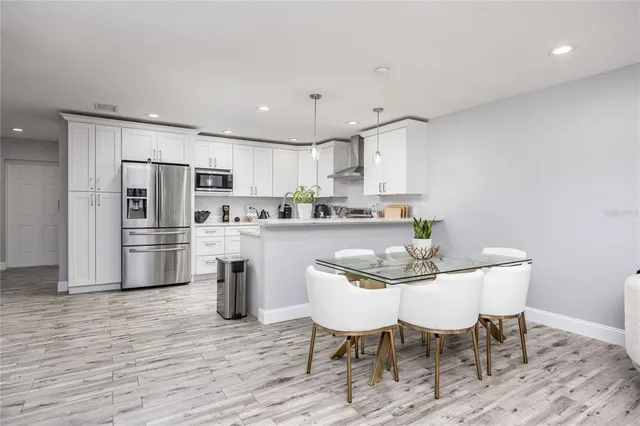 a kitchen with stainless steel appliances a dining table chairs microwave and sink