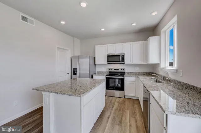 a kitchen with granite countertop a sink stove and refrigerator