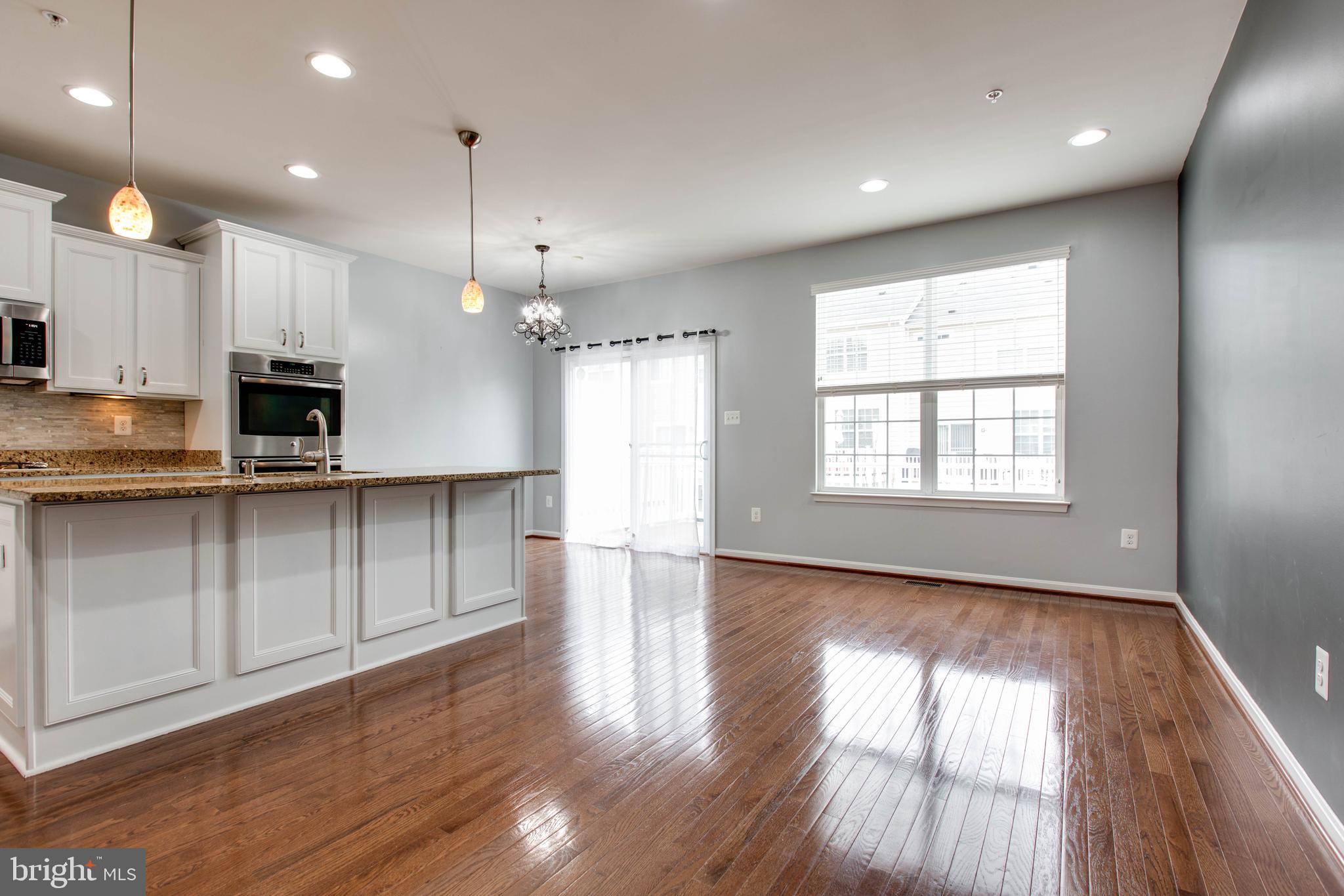 7926 Silver Oak Road Hanover, MD 21076 - Photo 13 of 44 an open kitchen with white cabinets wooden floor and a window
