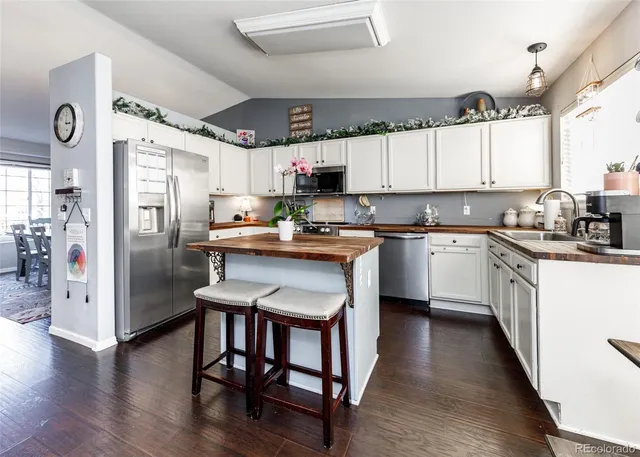 a kitchen with stainless steel appliances granite countertop a refrigerator a sink dishwasher a stove and white countertops with wooden floor