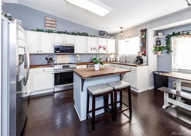 a kitchen with stainless steel appliances granite countertop a table chairs refrigerator and sink