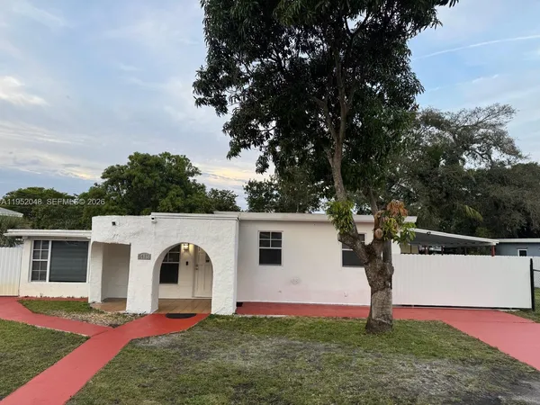 a view of a white house with a yard and large tree