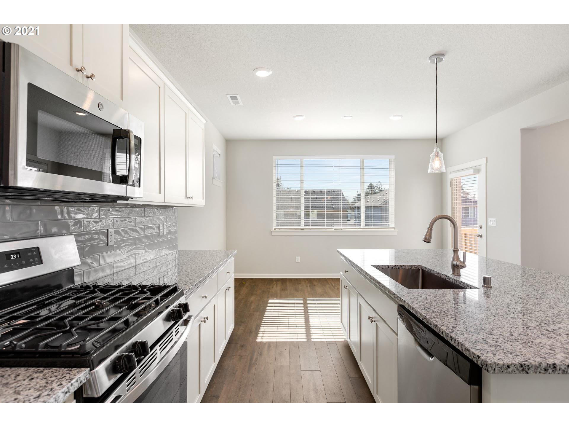 4227 South 38th Way Ridgefield, WA 98642 - Photo 6 of 14 a kitchen with granite countertop a stove a sink and a microwave