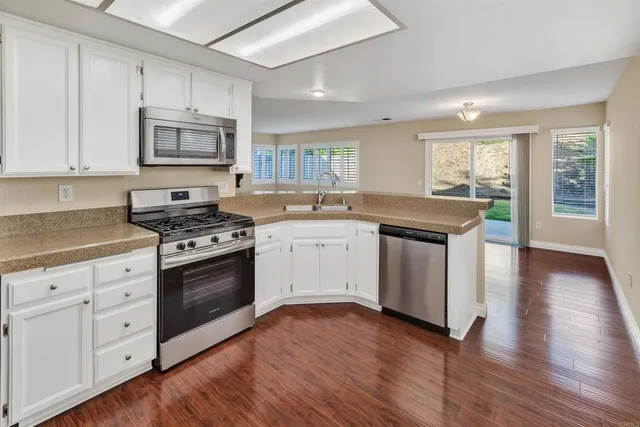 a kitchen with granite countertop a sink cabinets and wooden floor